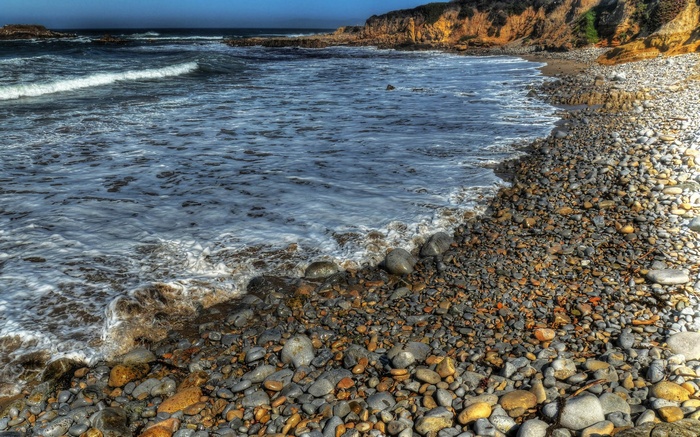 Pebble beach with waves and cliffs