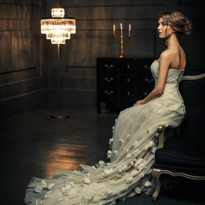 Woman in a white dress sitting in a dark room