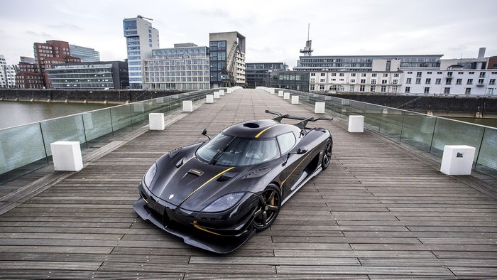 Black Koenigsegg One:1 supercar on a wooden pier
