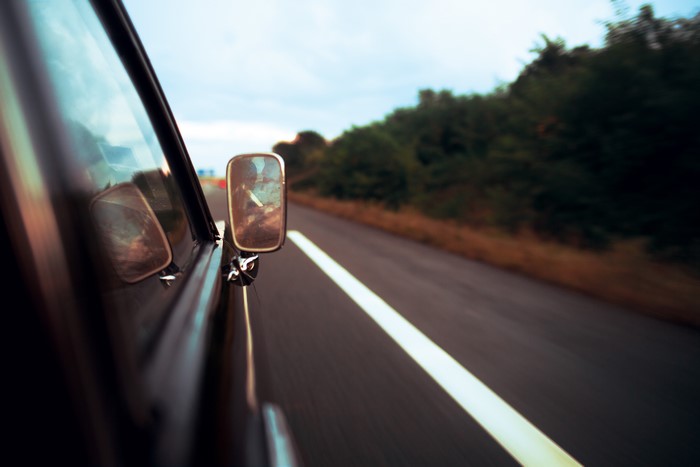 Car driving on a road with a side mirror