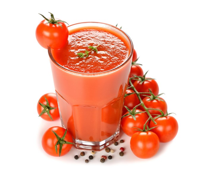 Tomato juice in a highball glass with tomatoes and peppercorns