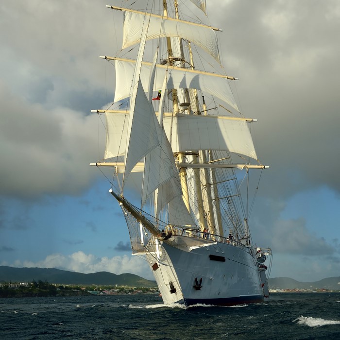 A large sailing ship with white sails on the sea
