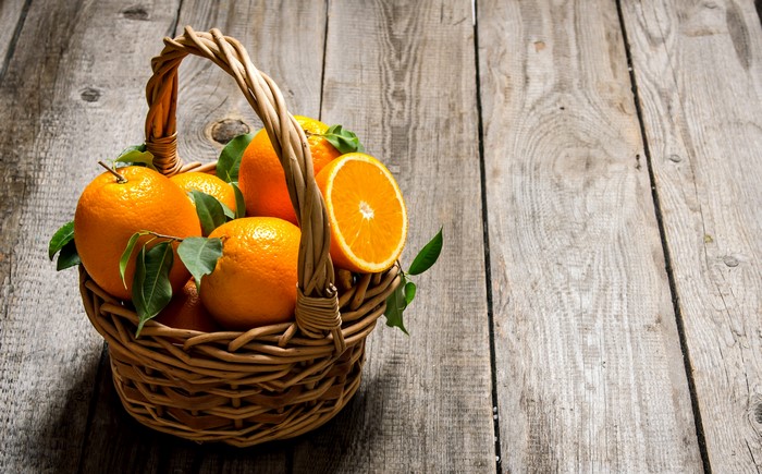 Oranges in a Wicker Basket on Wood Planks
