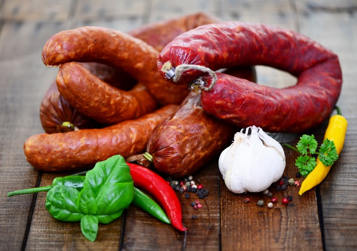 Sausages with garlic, chili peppers, and herbs on wood
