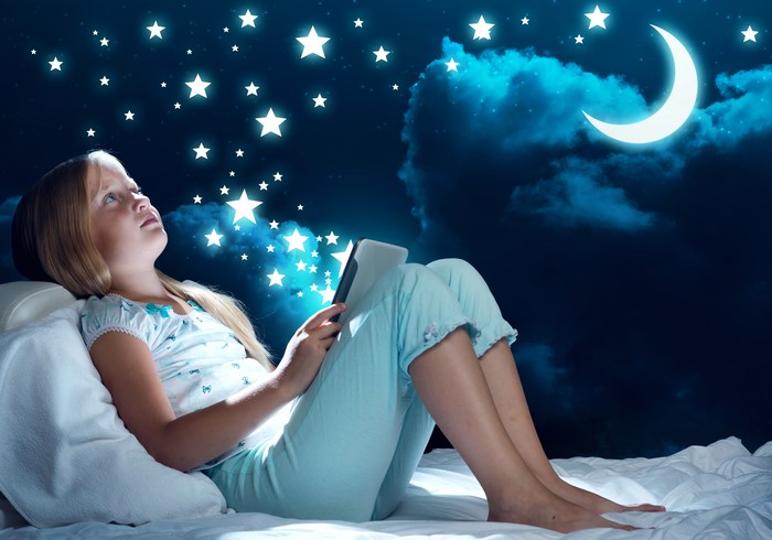 Girl with tablet looking at stars and moon