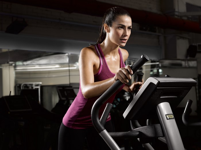 Woman exercising on an elliptical machine in a gym