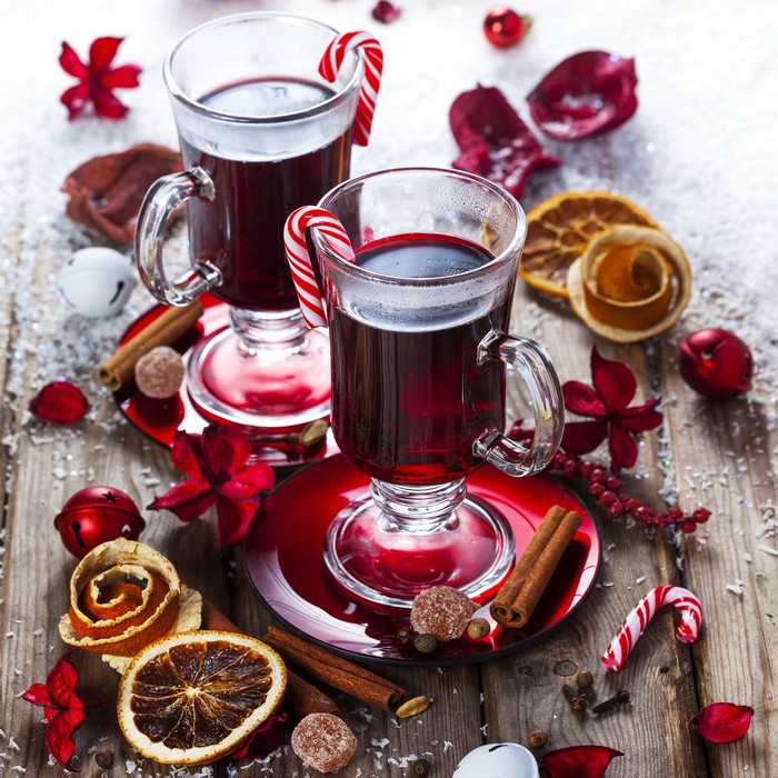 Two glasses of mulled wine with candy canes and cinnamon
