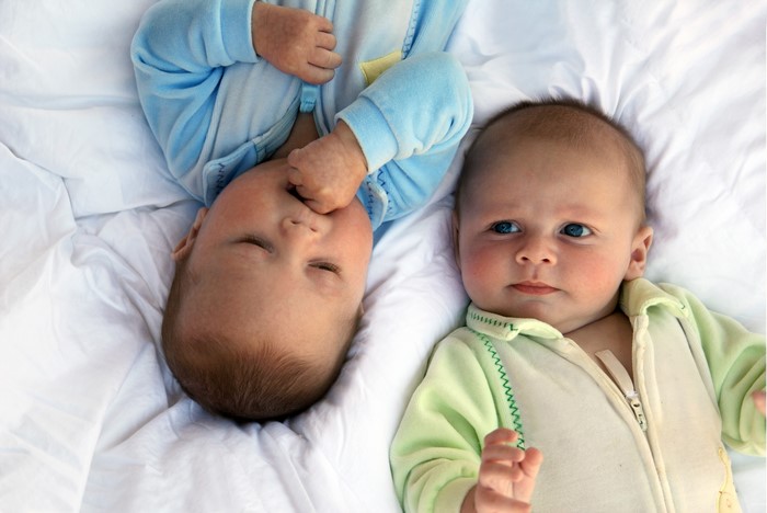 Two Infants Lying on White Blanket