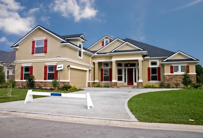 Tan stucco house with red shutters and a garage