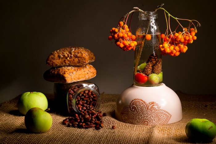 Still-life with apples, buns, nuts, and sorbus in a bottle