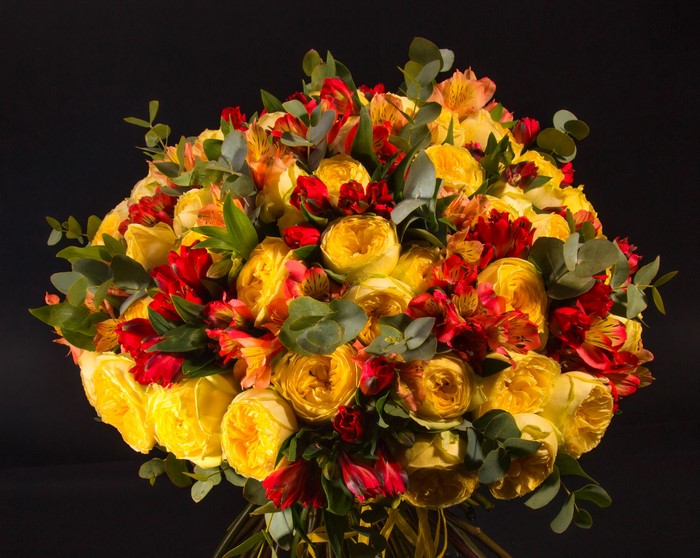 Bouquet of yellow peonies and red alstroemeria on black background