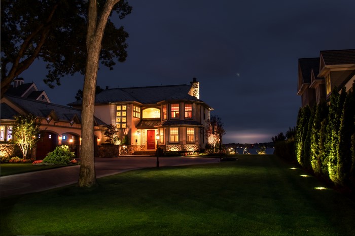 Luxury house at night with illuminated lawn and trees