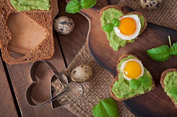 Heart-shaped avocado toast with fried quail eggs