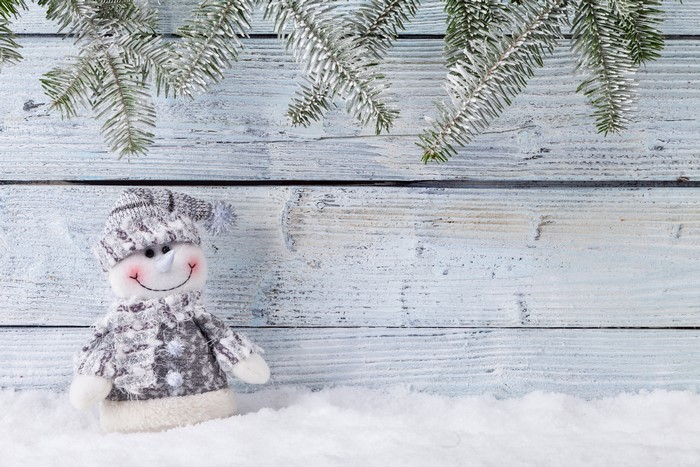 Snowman on wood planks with pine branches