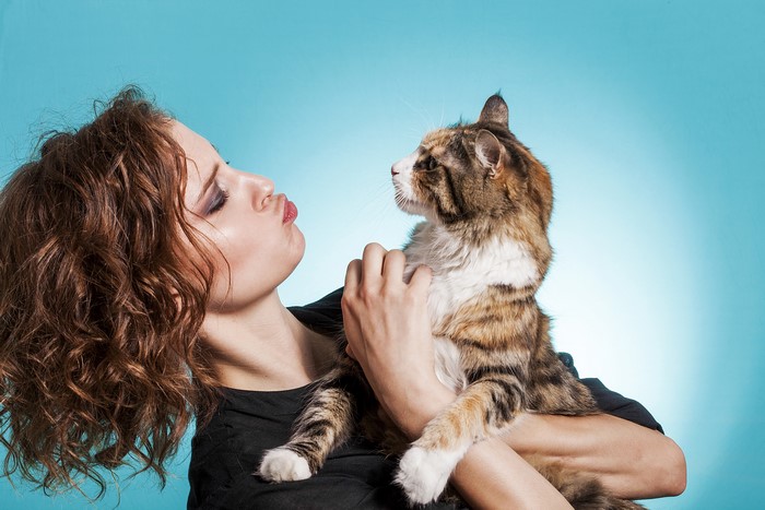 Woman with curly brown hair holding a cat