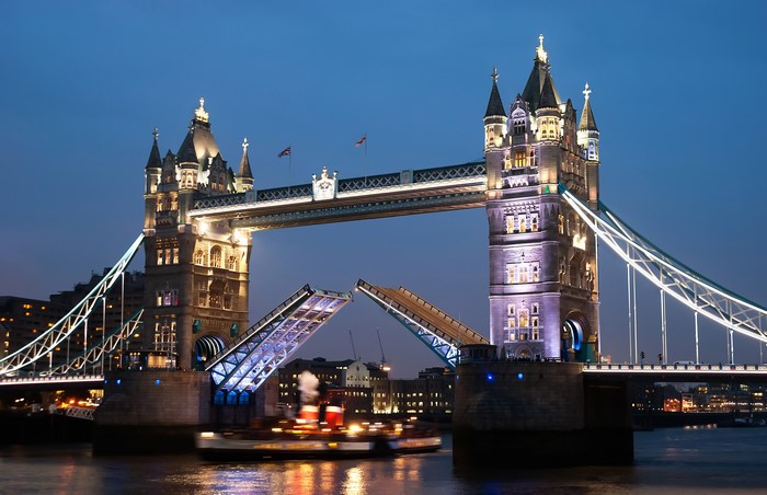 Tower Bridge opening at night with a boat passing