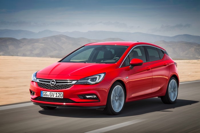 Red Opel Astra driving on a road