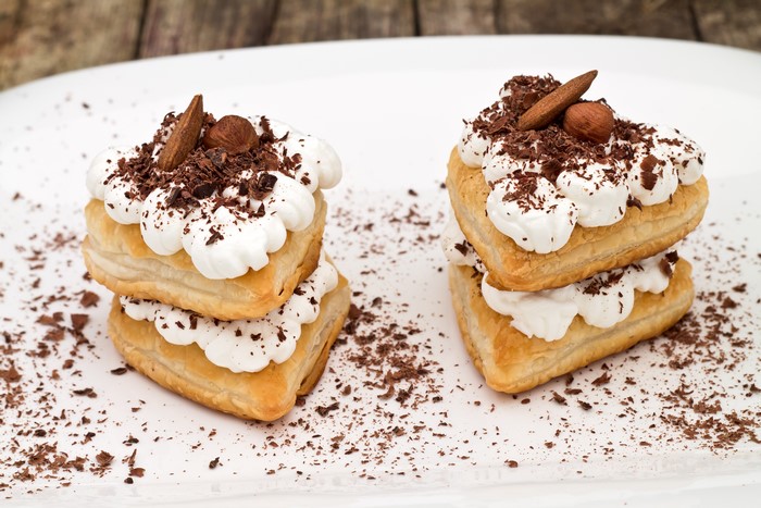 Two heart-shaped puff pastry cakes with cream and chocolate