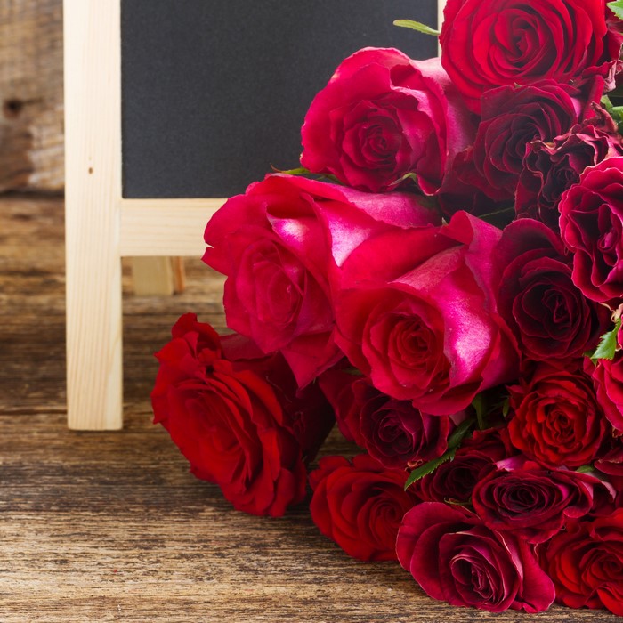 Red roses on a wooden surface with a chalkboard easel