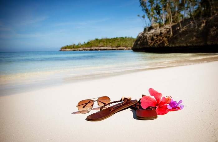 Beach scene with sunglasses, flip-flops, and flowers