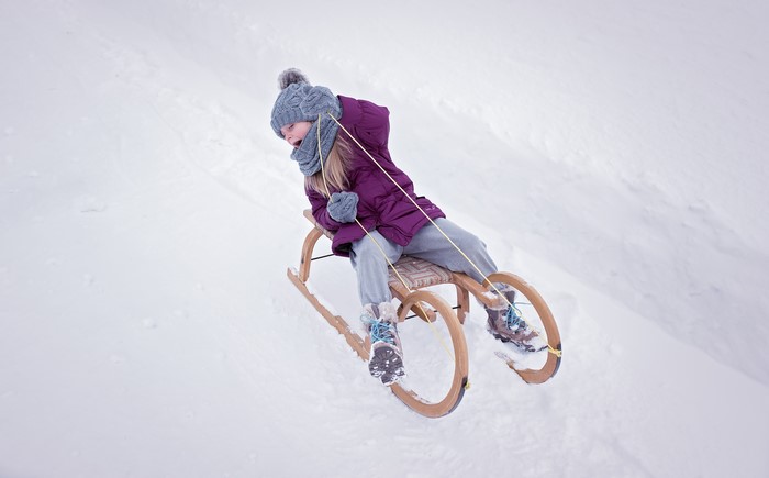Girl sledding down a snowy hill