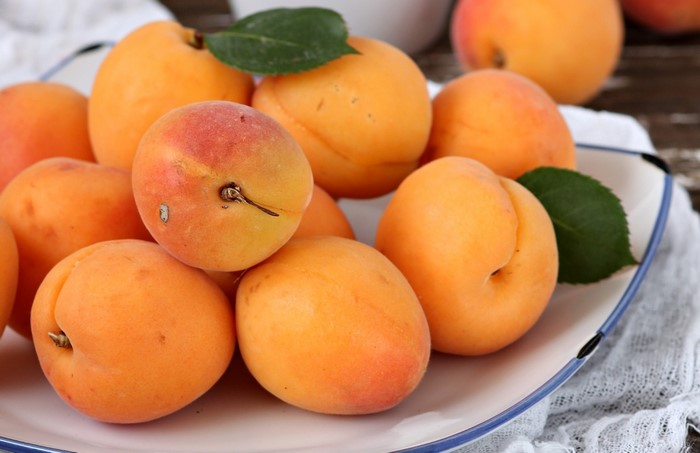 A pile of fresh apricots on a plate