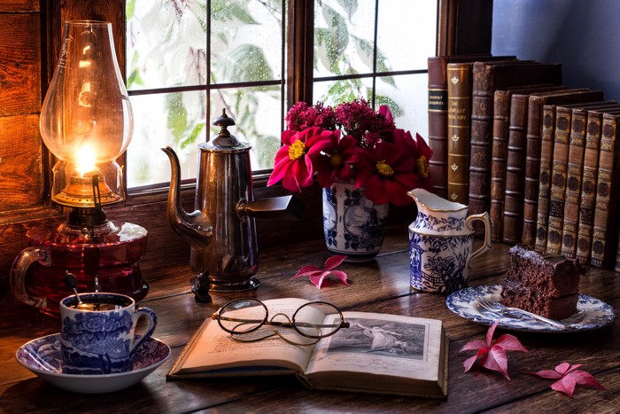 Still-life with kerosene lamp, books, and cake