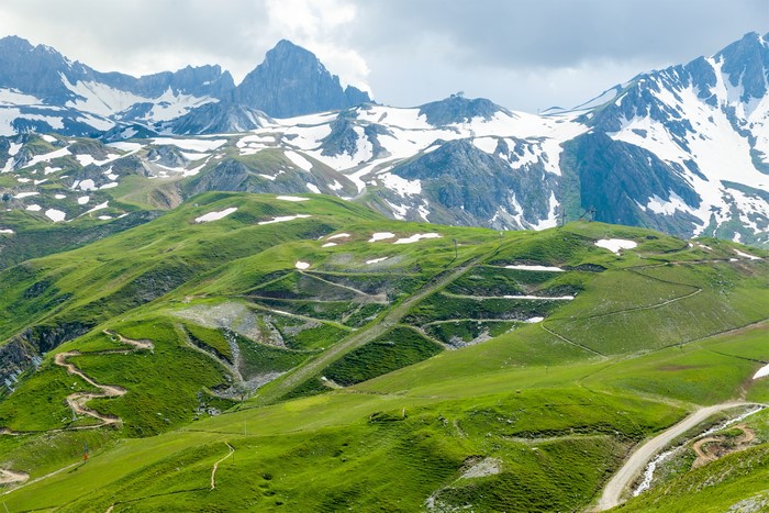 Green mountains with snow-capped peaks and winding paths