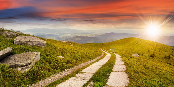 Mountain road with sun rays at sunset