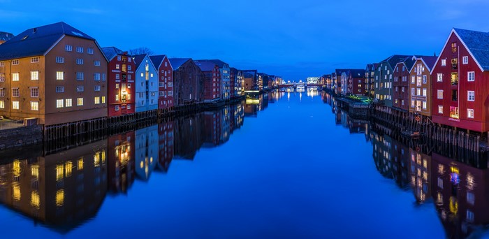 Colorful buildings reflecting in a canal at dusk in Trondheim, Norway
