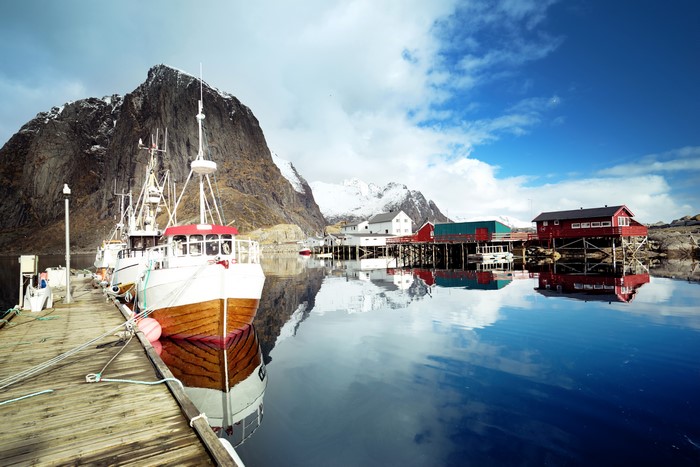 Fishing boats docked in Lofoten, Norway with mountain reflection