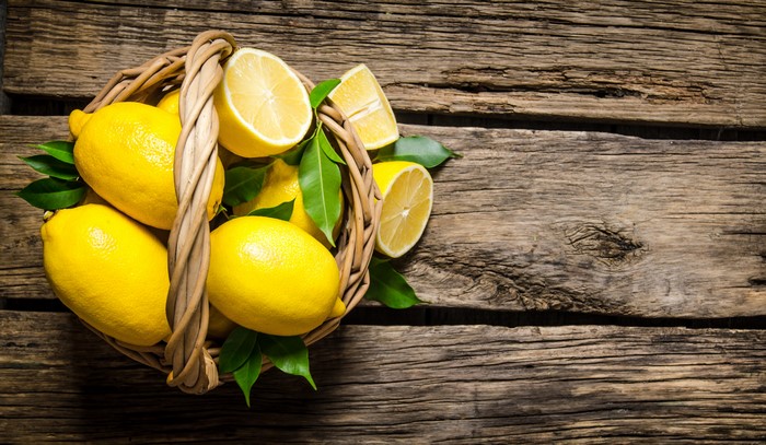 Lemons in a wicker basket on wood planks