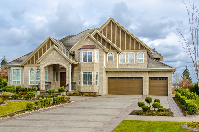 Luxury brick mansion with a three-car garage and manicured lawn