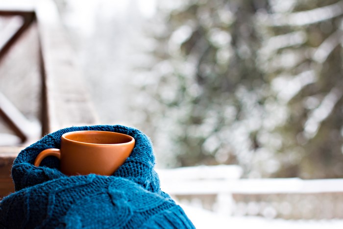 Cup of hot drink wrapped in a blue scarf in winter