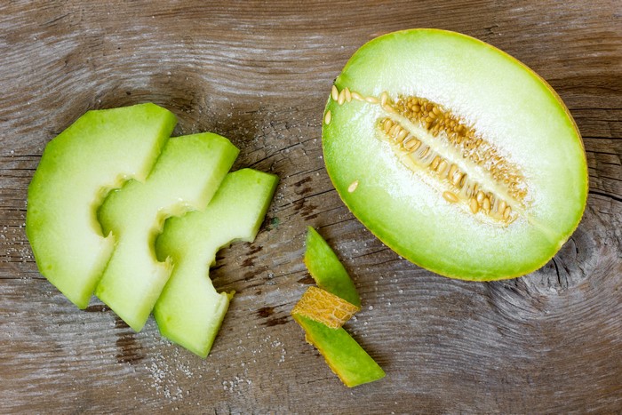 Melon slices and half melon on wood