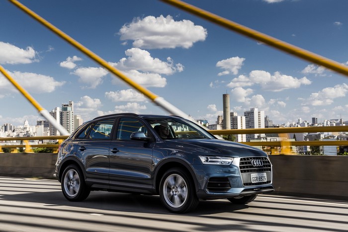 Blue Audi Q3 on a bridge with city skyline