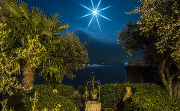 Night view of Sirmione, Lombardy, Italy with moon and palm trees