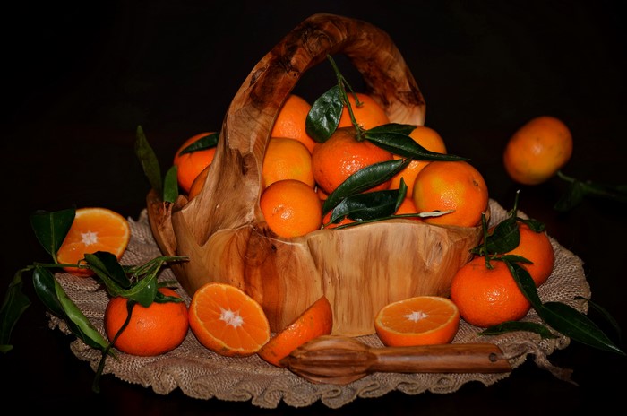Mandarin oranges in a wooden basket with a juicer