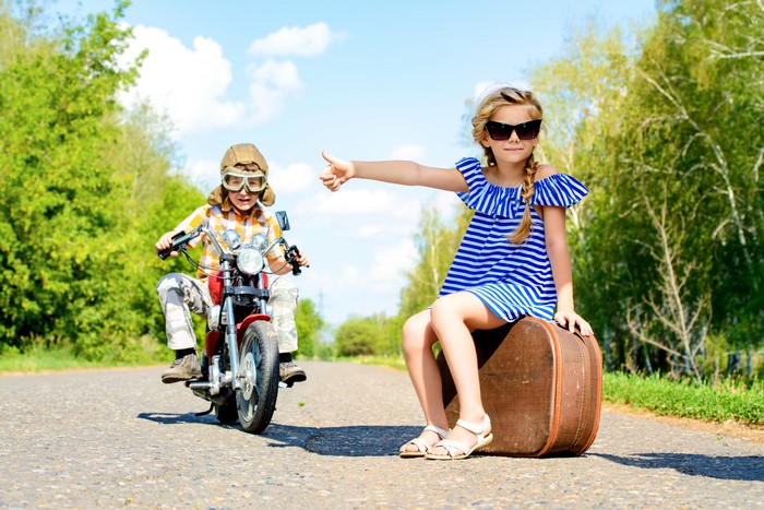 Children on a motorcycle and suitcase on a road