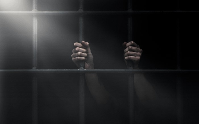 Hands gripping prison bars