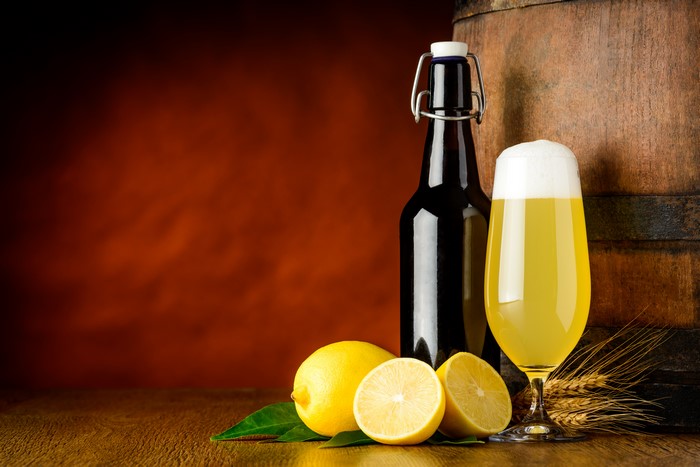 Beer bottle, glass, lemons, and barrel