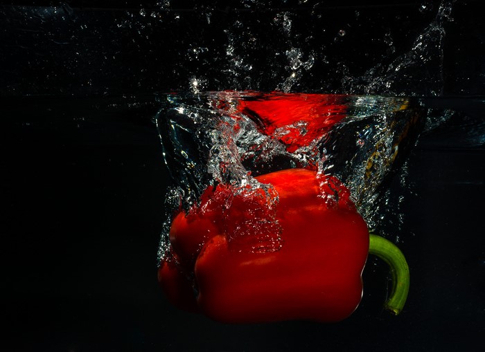 Red bell pepper splashing into water