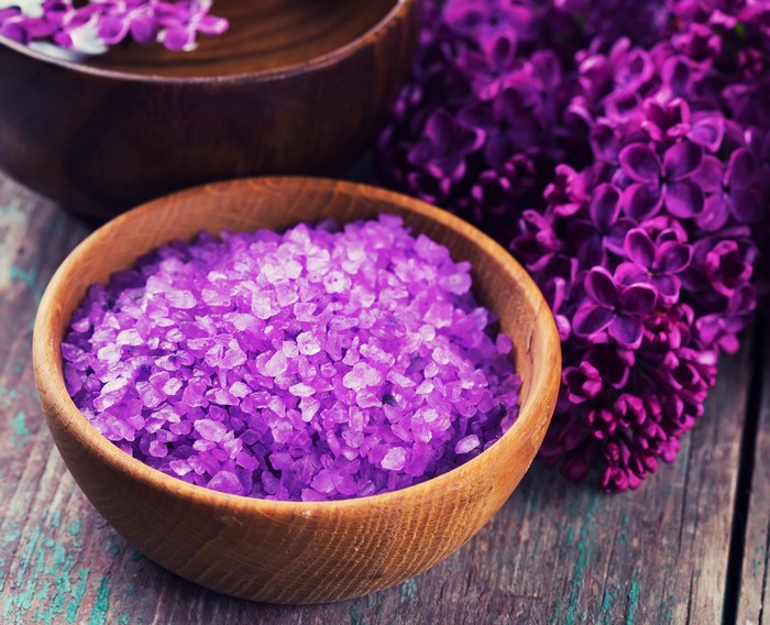 Purple bath salts and lilac flowers in wooden bowls