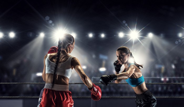 Two female boxers in a ring with spotlights