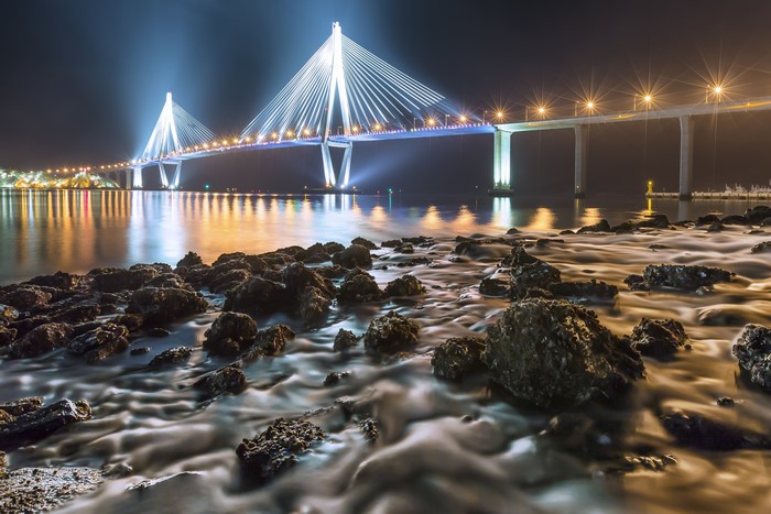 Cable-stayed bridge at night with rocky shore