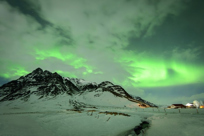Aurora Borealis over Snowy Mountains in Iceland