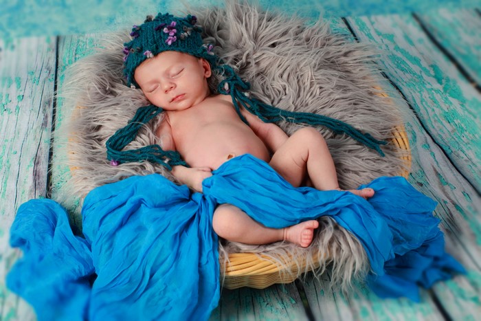 Newborn baby sleeping in a basket with blue fabric