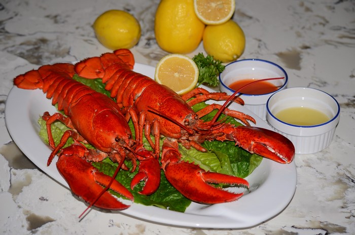 Two Lobsters on a Plate with Lemons and Dips