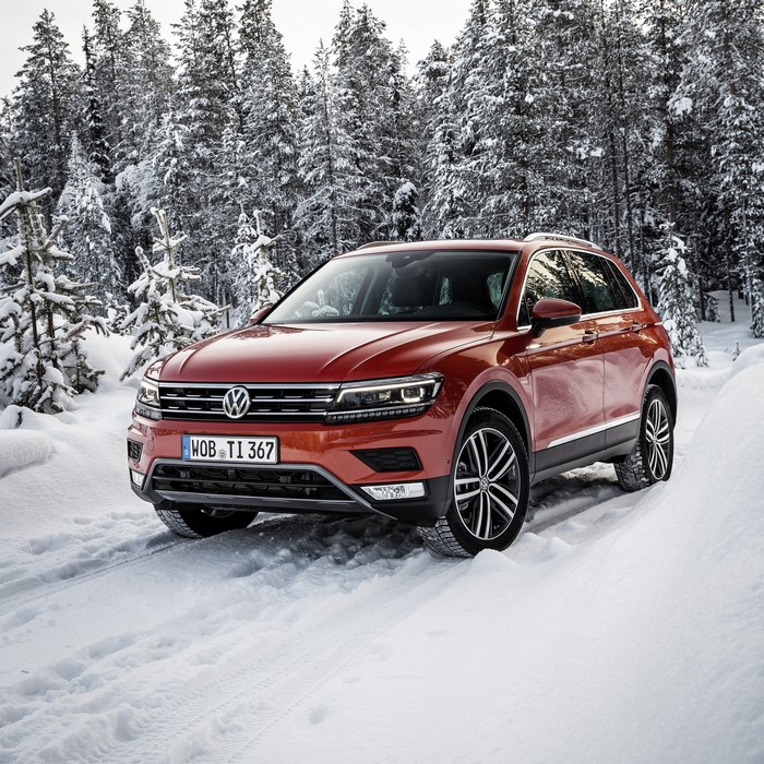 Orange Volkswagen Tiguan driving in a snowy forest