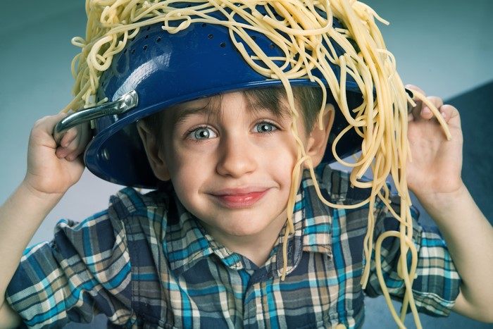 Boy wearing a colander with spaghetti on his head